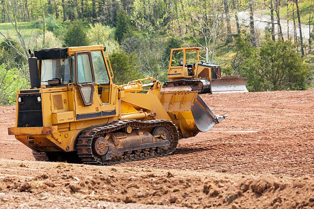 Land being levelled and cleared by yellow earth moving digger